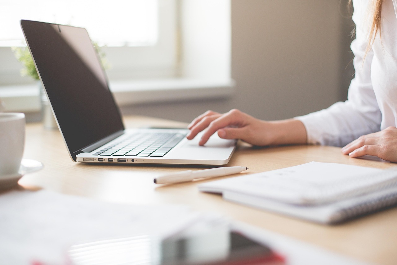 Personne réfléchissant à sa reconversion professionnelle devant un carnet et un ordinateur