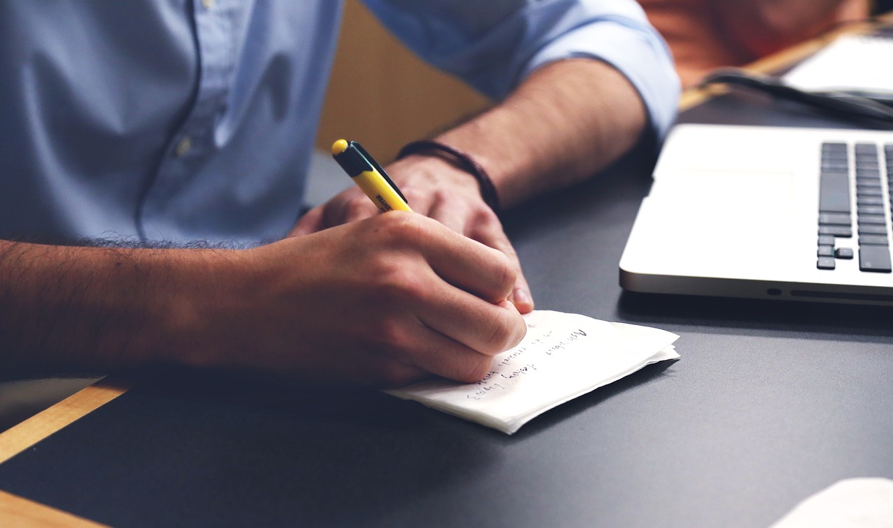 Professionnel prenant des notes à côté d'un ordinateur portable